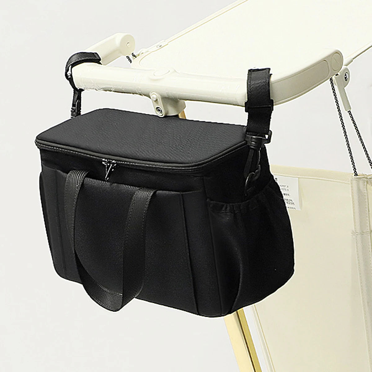 Black pram organiser bag with bottle holders strapped to a pushchair handle