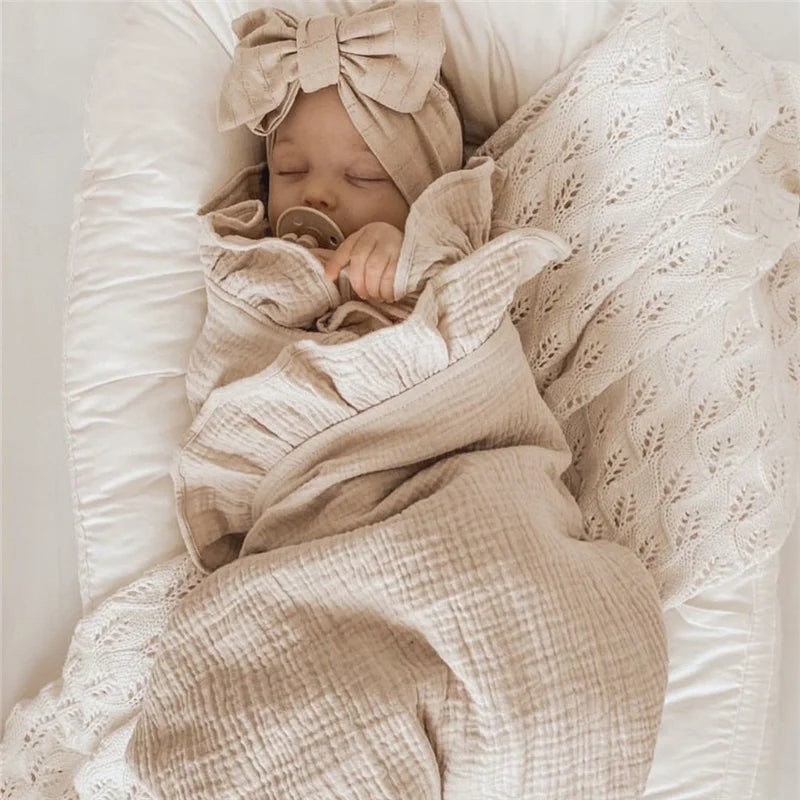 Newborn baby wrapped in a plain neutral cotton muslin blanket
