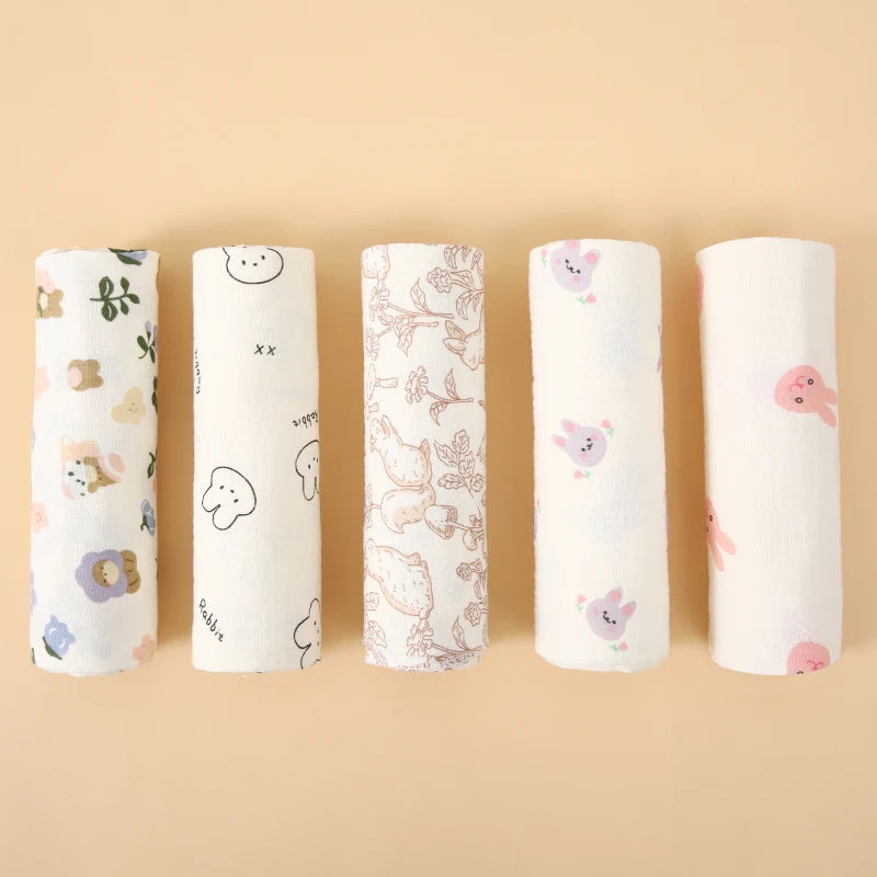 Five rolled cotton muslin swaddle blankets in soft prints